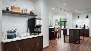 A modern kitchen with a herringbone tile backsplash, a coffee machine, and a wooden cutting board. - Hampton Inn Towson Downtown (Towson)