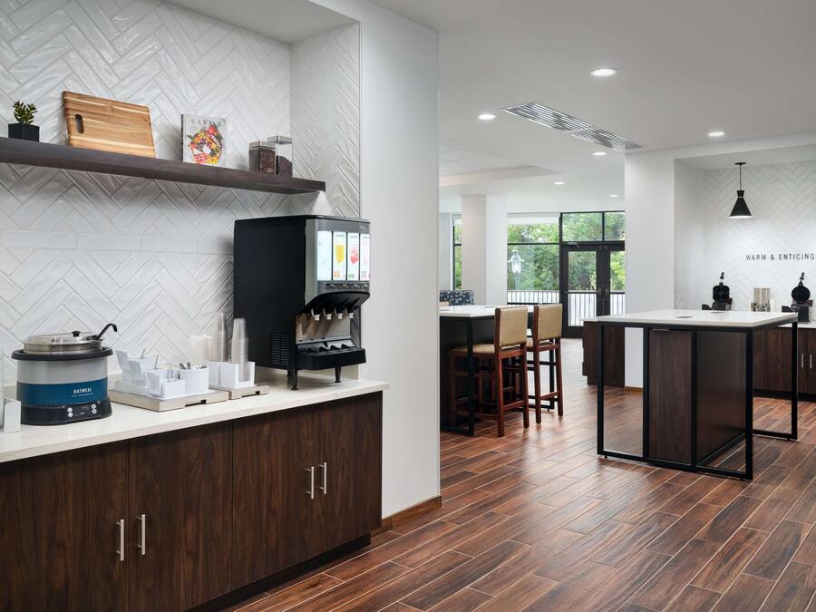 A modern kitchen with a herringbone tile backsplash, a coffee machine, and a wooden cutting board.
