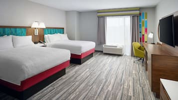 Habitación de hotel con dos camas, un escritorio, una silla, un televisor y una ventana con cortinas.