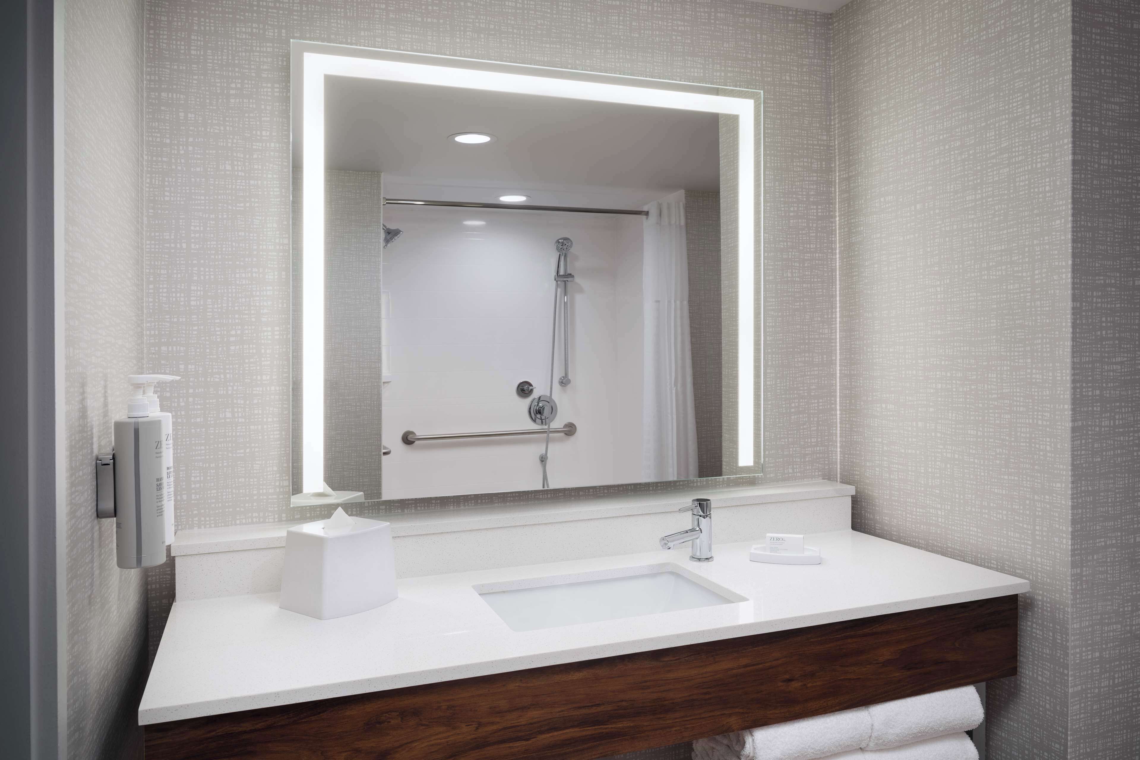 Un baño moderno con un lavamanos blanco, un espejo y una ducha.