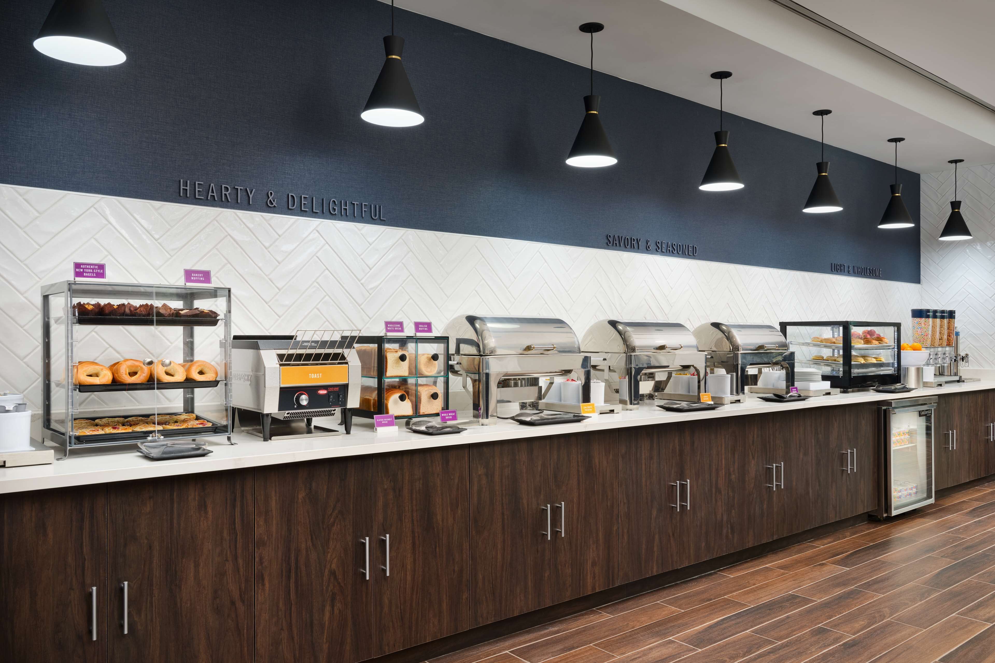Disposição de buffet com diversos pontos de comida, incluindo uma mesa com donuts e uma máquina de café.