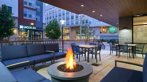 An outdoor seating area with a fire pit, blue sofas, and tables. - Hampton Inn Towson Downtown (Towson)