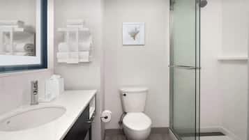 A modern bathroom with a white sink, toilet, and glass shower enclosure.