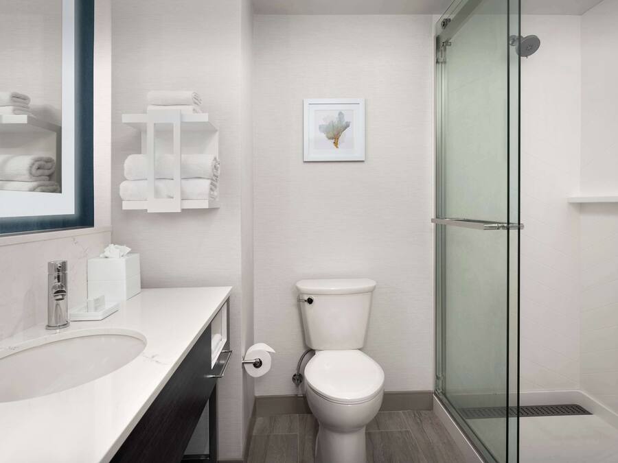 A modern bathroom with a white sink, toilet, and glass shower enclosure.