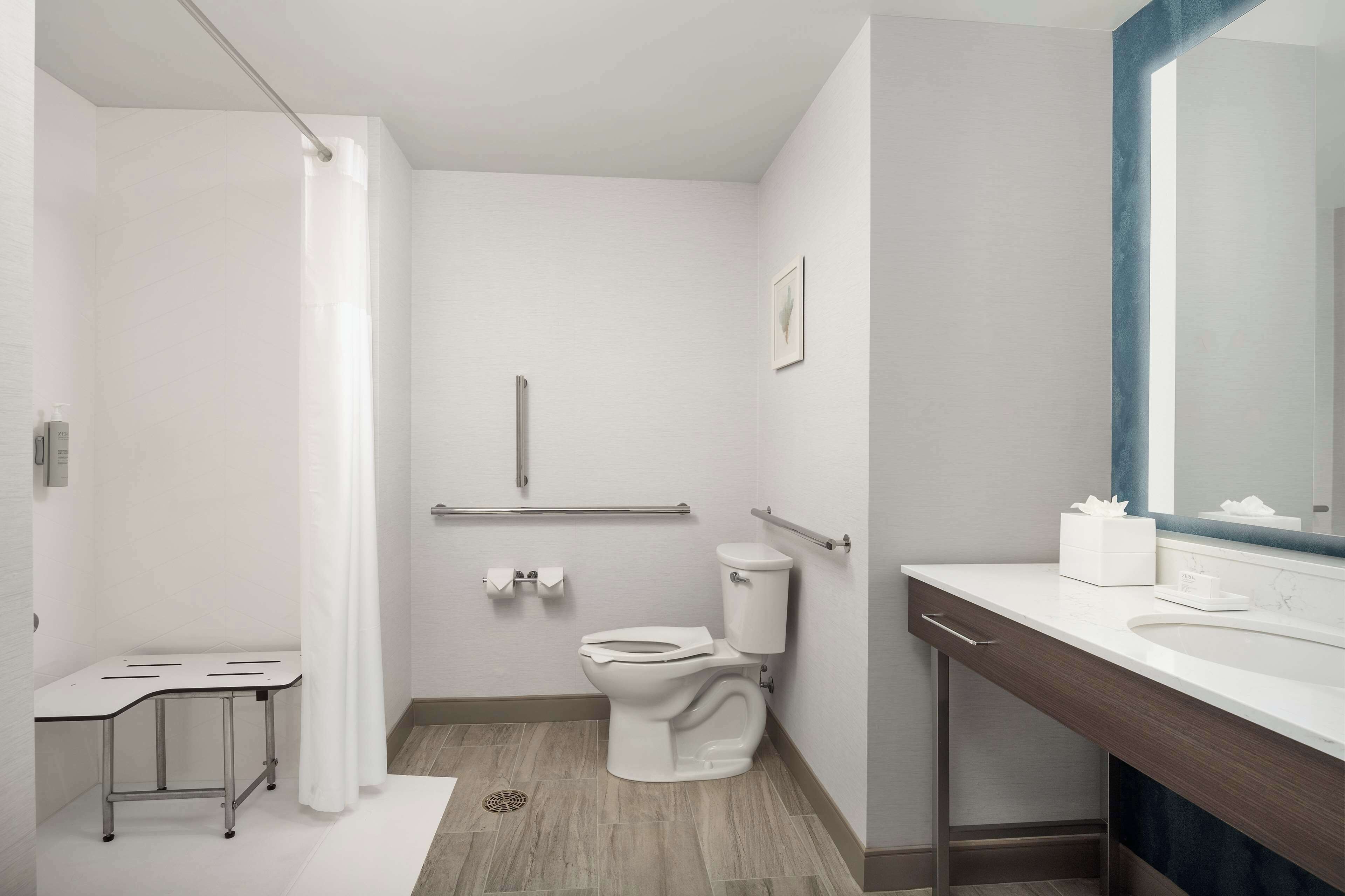 Un baño moderno con inodoro, lavabo, zona de ducha y una pequeña mesa.