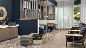 Un salon moderne comprenant un ensemble de canapés, des poufs, une table basse et un miroir décoratif.