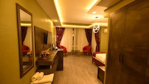 A hotel room with a wooden floor, a bed, a desk with a mirror, a chair, and a TV. - Swiss Inn Hotel Mersin (Mersin)