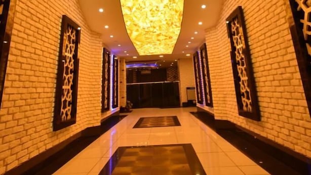 A hotel corridor with a high ceiling, brick walls, and a reflective floor. - Swiss Inn Hotel Mersin (Mersin)