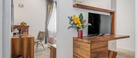A modern room with a wooden desk, a TV, and a vase of flowers.