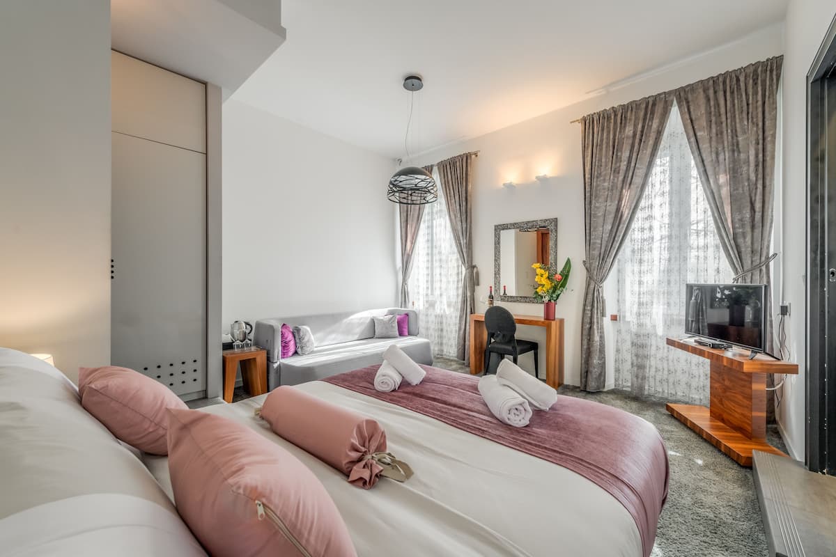 Una habitación de hotel moderna con una cama grande, un escritorio, un televisor y un espejo.