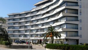 Un hotel de varios pisos con un diseño arquitectónico moderno, que cuenta con balcones en cada planta.