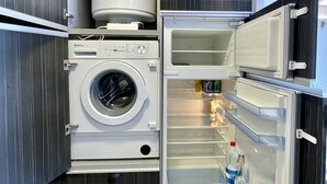 Un appareil combiné lave-linge et sèche-linge compact, doté d’un compartiment réfrigérateur intégré.