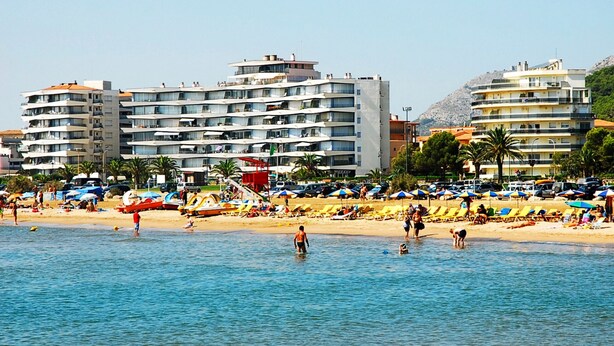 Un hôtel situé sur la côte, avec plusieurs étages, des balcons et un emplacement en bord de mer.