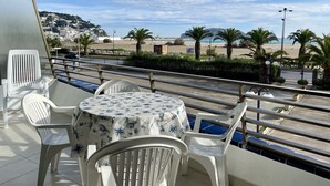 Un balcon avec une table et des chaises, donnant sur une plage et offrant une vue sur la ville.
