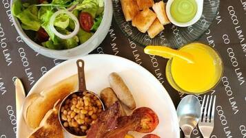 A breakfast plate with eggs, bacon, beans, sausages, toast, and a salad.