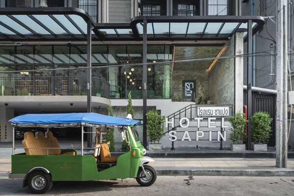 A green and brown tuk-tuk parked in front of a hotel named "HOTEL SAPIN". - Hotel Sapin (Bangkok)