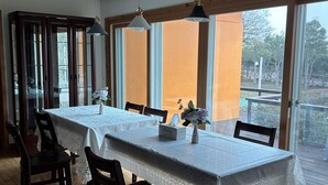 A dining area with a long table, chairs, and pendant lights. - Betta's Homestay (Jeju City)