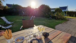 Un conjunto de mesa y sillas de madera para picnic al aire libre, con comida y bebidas, rodeado de follaje y un cielo despejado.