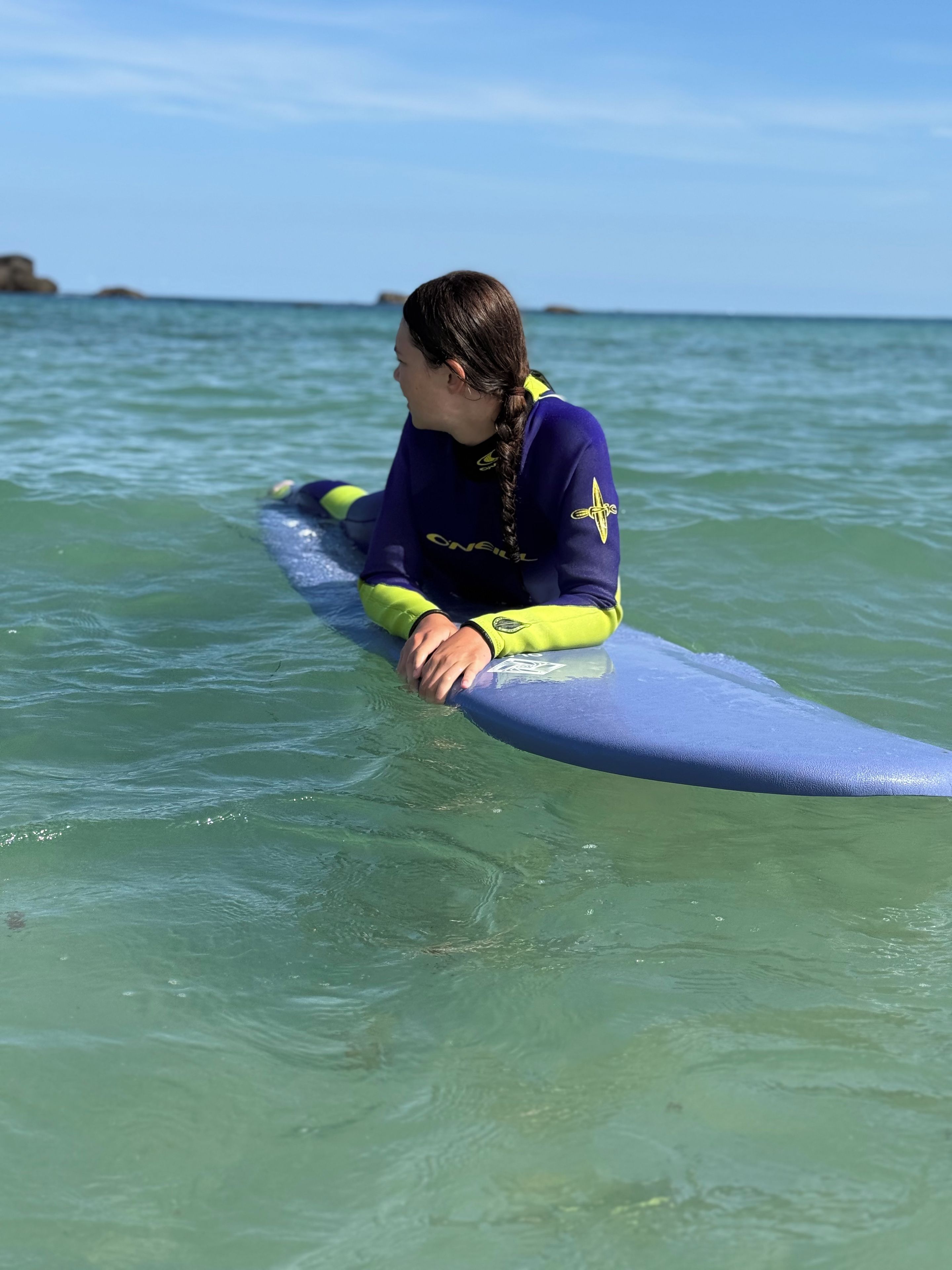 A person sitting on a surfboard in the water.