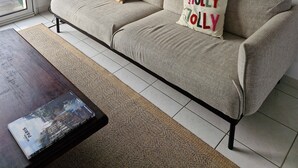 Un salón con un sofá color beige, una mesa de centro y una estantería. Hay tres cuadros enmarcados en la pared.