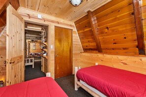 A cabin with two beds, a wooden interior, and a small kitchenette. - Pine Haven By Destination Big Bear: Close to the Village, Snow Summit and Marina's (Big Bear Lake)