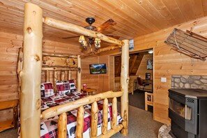 A log cabin room with a bed, a fireplace, and a television.