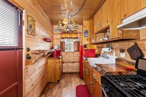 A compact kitchen with wooden cabinets, a stove, and a sink. - Pine Haven By Destination Big Bear: Close to the Village, Snow Summit and Marina's (Big Bear Lake)