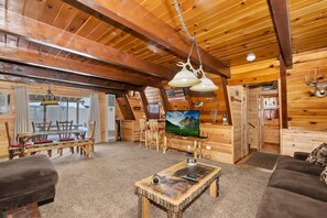 A log cabin interior with a dining area, a television, and a mounted deer head. - Pine Haven By Destination Big Bear: Close to the Village, Snow Summit and Marina's (Big Bear Lake)