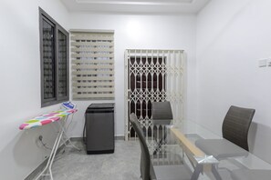 Compact room with a glass table, single chair, and small appliance.