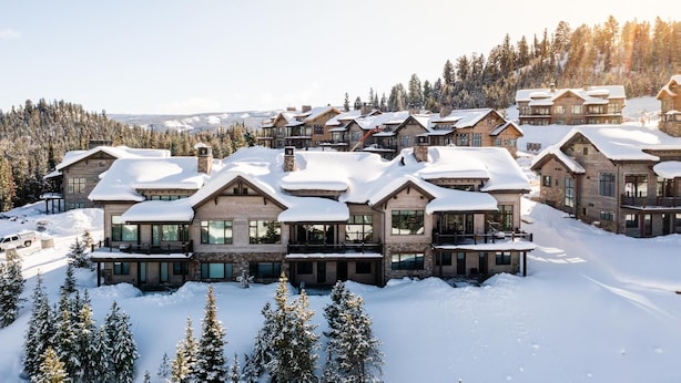 Un resort cubierto de nieve con varios edificios de estilo chalet, cada uno con grandes ventanales y balcones.