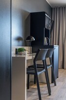Una kitchenette moderna con un armario negro, una planta pequeña en la encimera y dos sillas negras.
