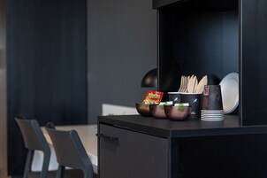 Una kitchenette con una cafetera, un tazón de botanas y una taza de café.