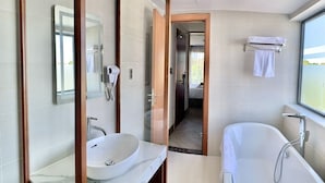 Ein modernes Badezimmer mit einem großen Spiegel, einem Waschbecken, einer Badewanne und einem Handtuchhalter.