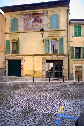 A building with a cobblestone street in front, a closed garage door, and a no parking sign.