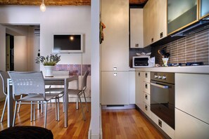 A modern kitchen with a dining area, a flat-screen TV, and a microwave.