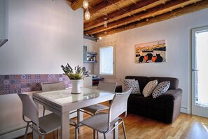 A modern living space with a dining area, a sofa, and a painting on the wall.