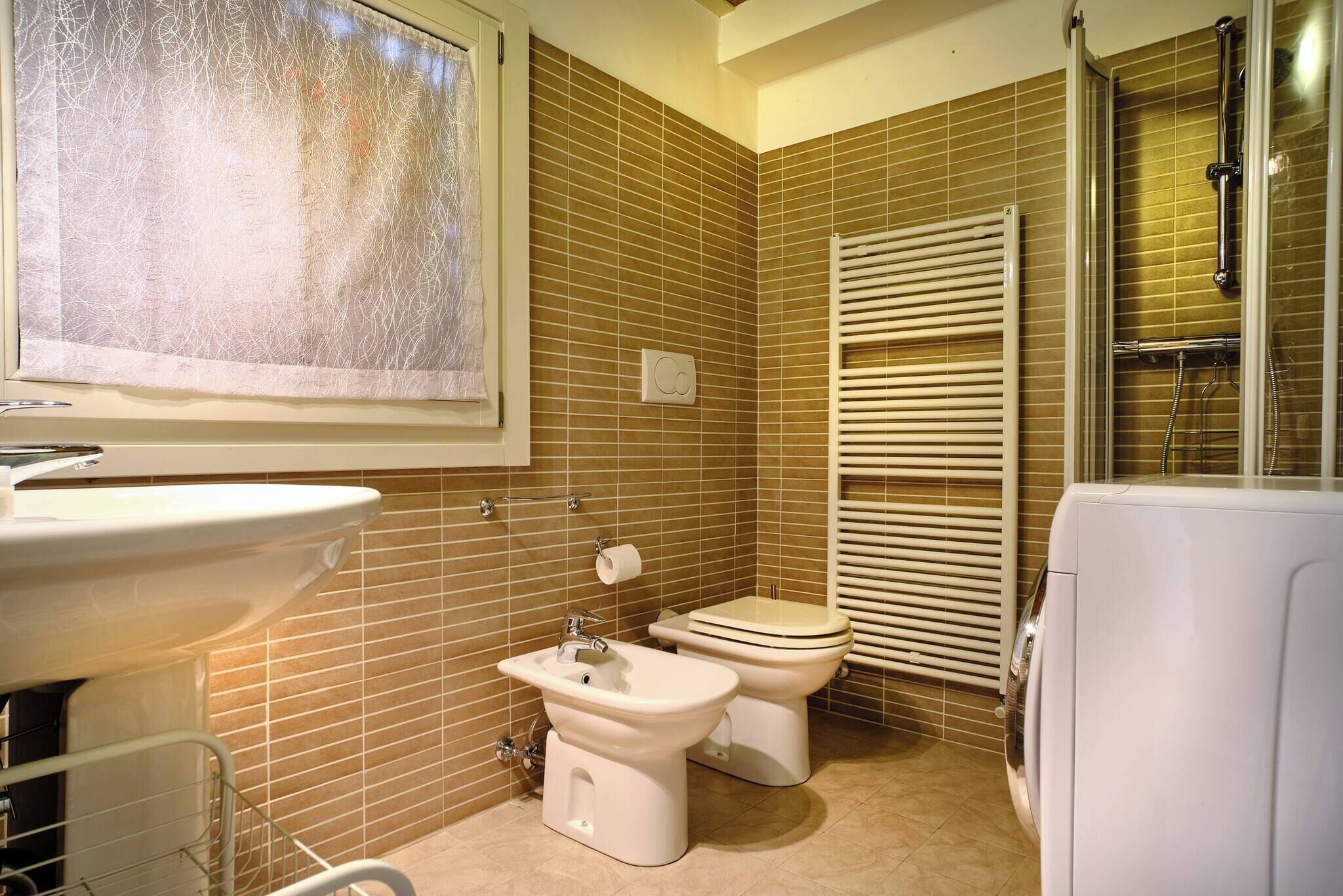 A bathroom with a sink, two toilets, a bidet, and a shower area.