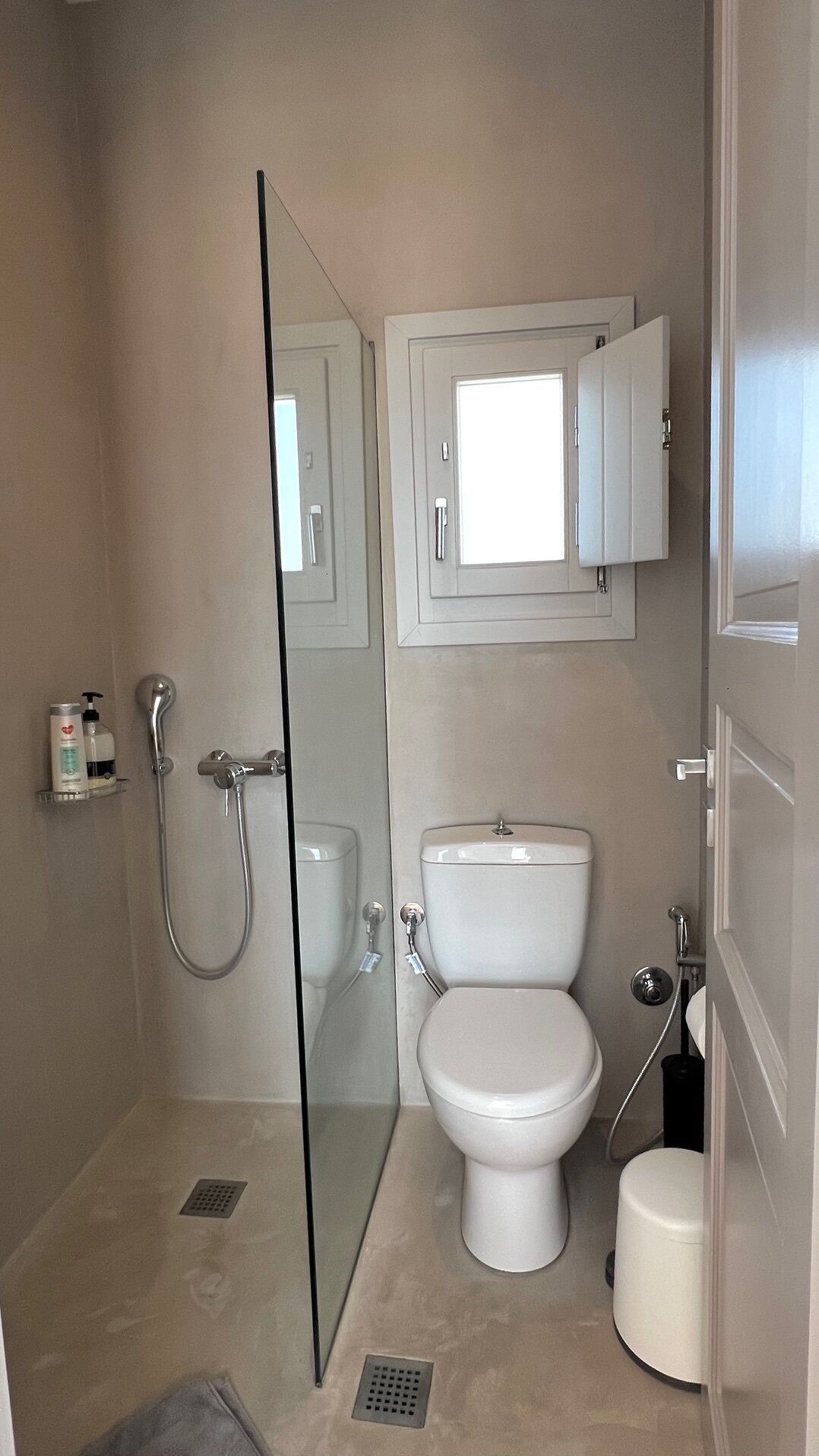 A bathroom with a glass shower enclosure, a toilet, and a sink.