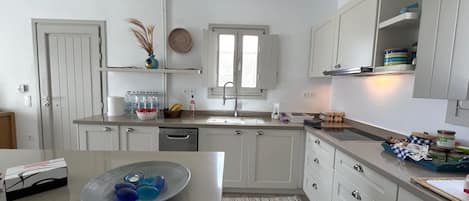 A modern kitchen with white cabinets, a stainless steel sink, and a window above the countertop.