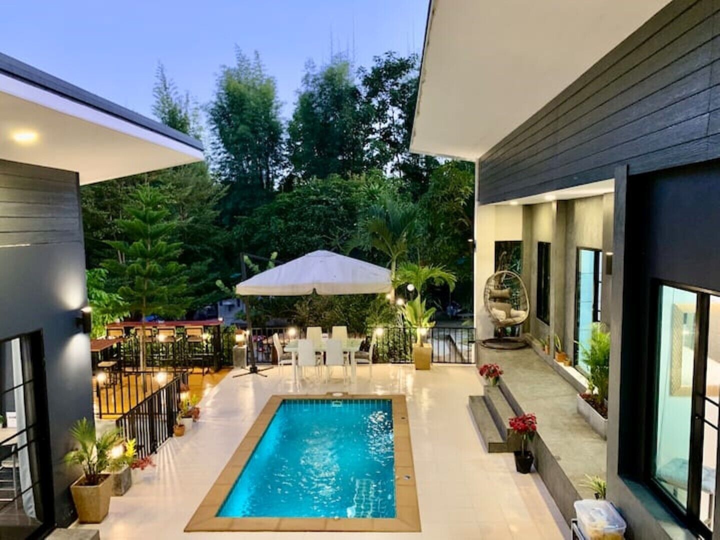 An indoor swimming pool with a tiled floor, surrounded by seating areas and potted plants.