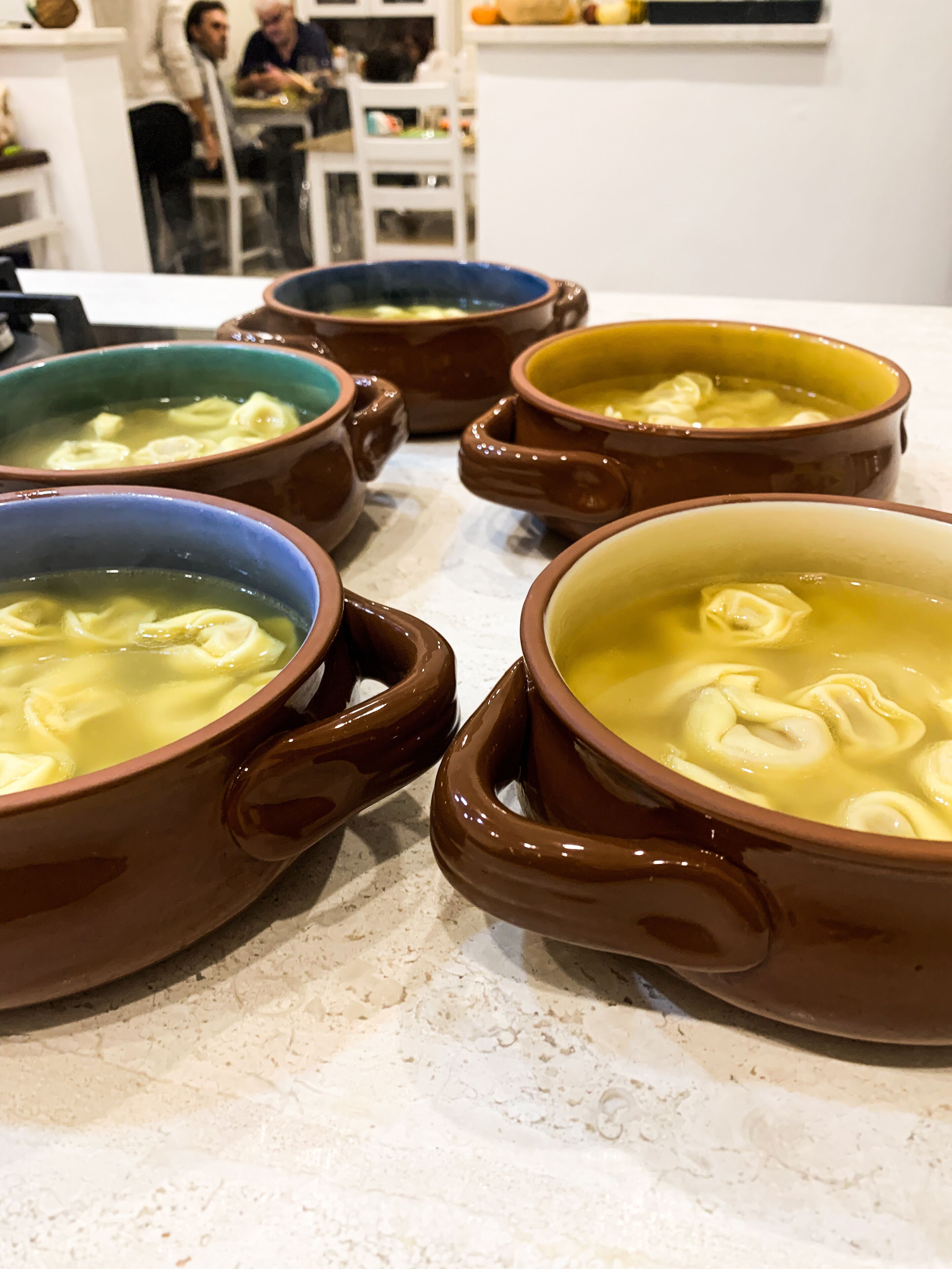 Four ceramic soup bowls with handles on a countertop.