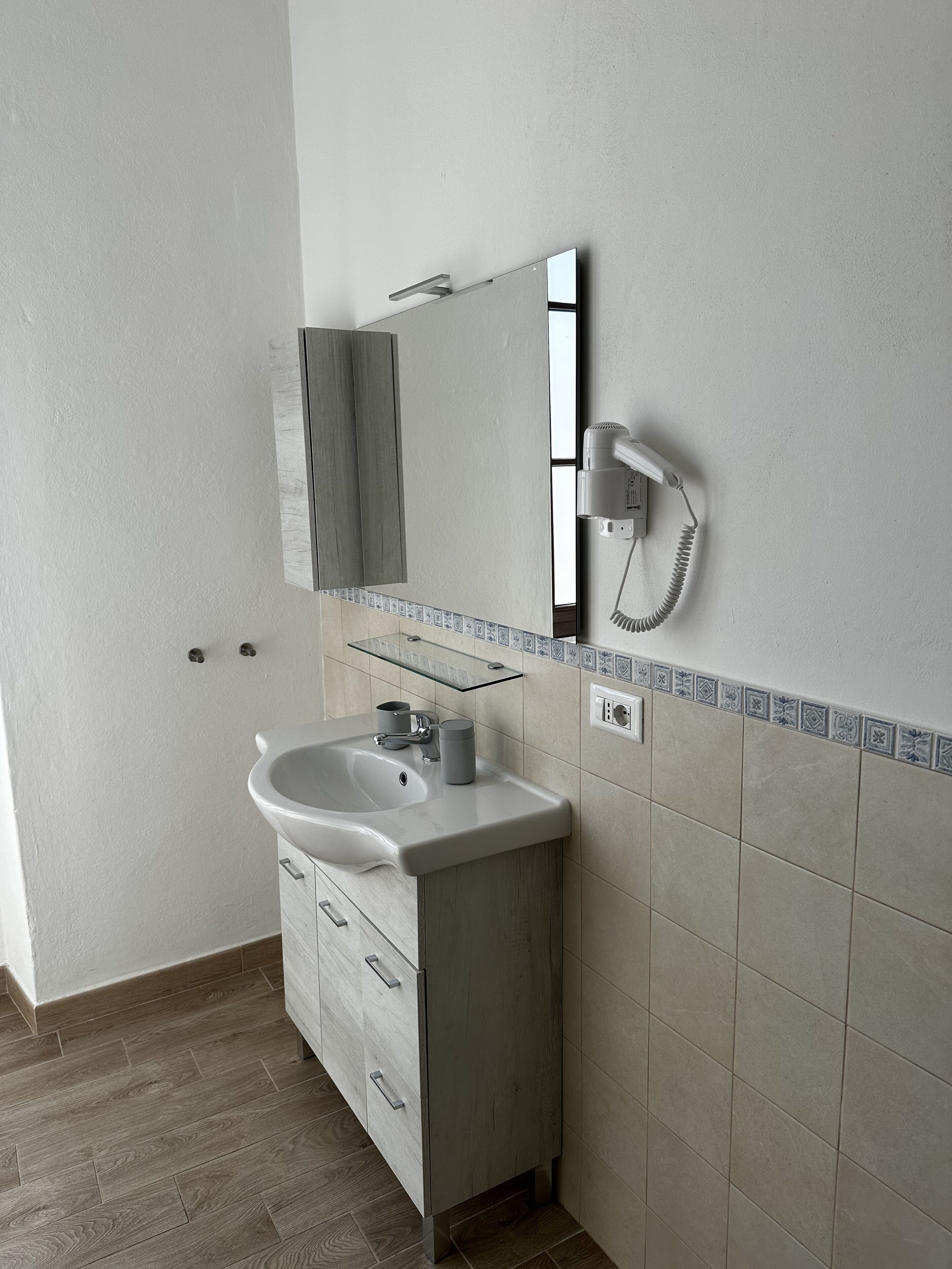 Ein Badezimmer mit Waschbecken, Spiegel und Wandhaartrockner.