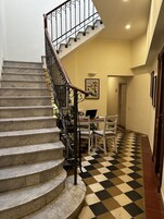 Una escalera con piso a cuadros que lleva a un comedor con una laptop sobre una mesa.