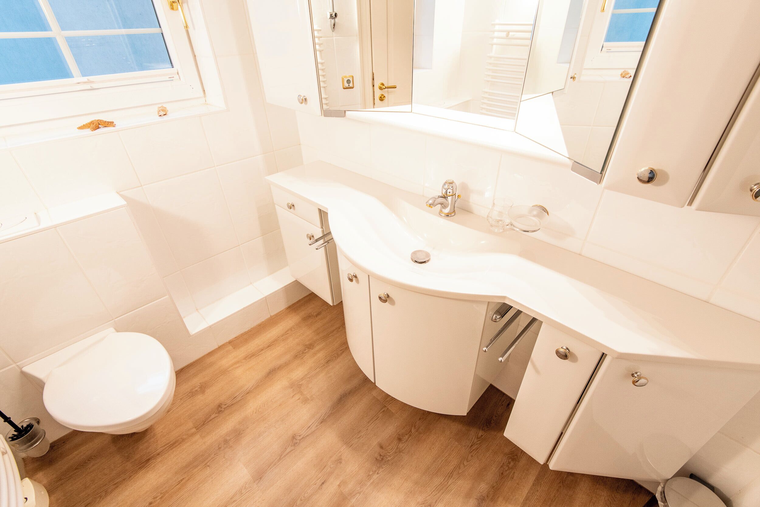 Un baño moderno con lavamanos, tocador y retrete blancos.