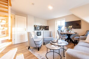Relax in this inviting space with a sofa, armchairs, and dining table for two, plus a modern kitchen and large flat-screen TV.