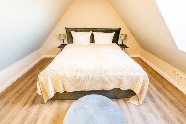 A bedroom with a bed, two bedside tables, and a nightstand. - Familie. Strandnah. Balkon. Objekt-id: Tow/09/03 (Westerland)