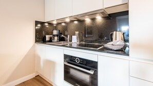 Una cucina moderna con pensili bianchi, una lavastoviglie Bosch, un forno integrato e un bollitore in acciaio inossidabile.