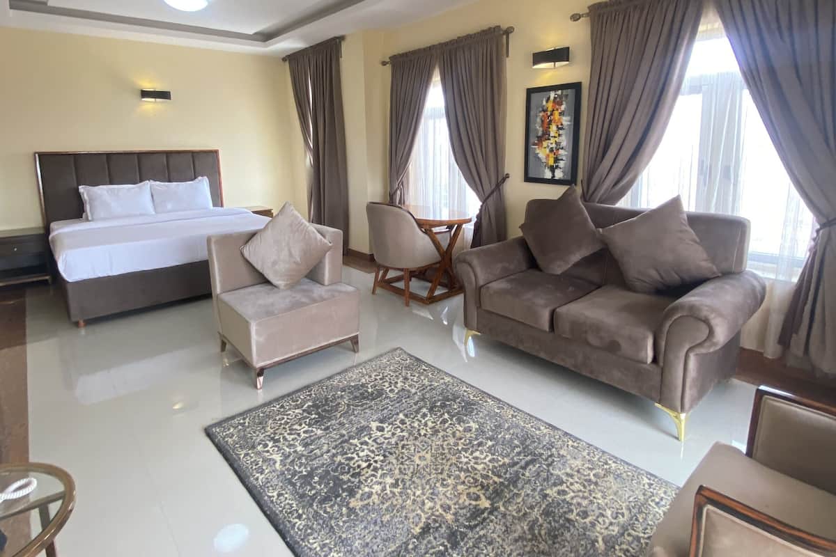 A hotel room with a bed, two sofas, a coffee table, and a rug.