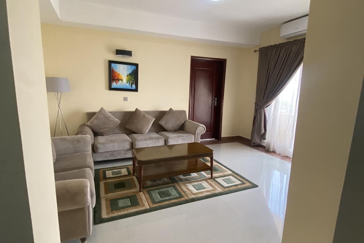 A living room with a sofa set, a coffee table, a rug, and a painting on the wall.