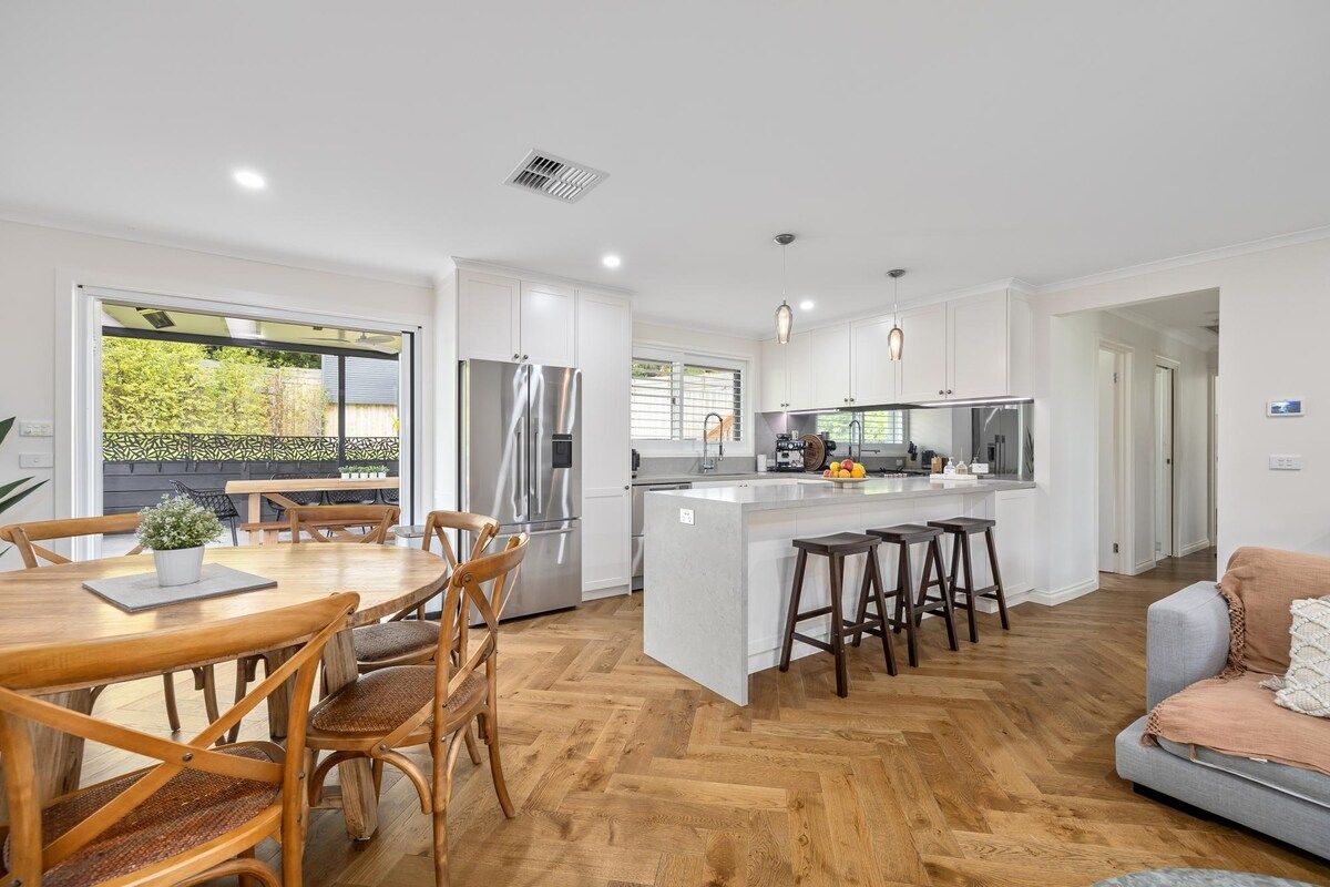 A modern kitchen with white cabinets, stainless steel appliances, and a central island with stools.